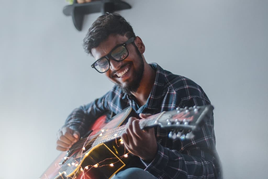 smiling man playing a guitar and doing his passion during free time